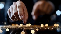 Hand touching glowing golden lights creating magical sparkle effect with bokeh background for luxury design and festive decoration concepts.