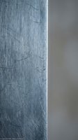 Scratched metal surface with fine linear marks and weathered texture showing industrial wear and aging patterns on steel or aluminum material.