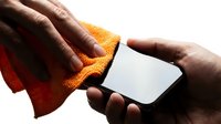 Hands holding blank white smartphone with orange and red cloth, isolated on white background for app mockup and mobile device marketing.