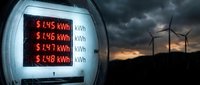 Digital electricity meter displaying rising energy costs with wind turbines generating renewable power under dramatic stormy sky at sunset.