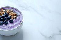 Purple smoothie bowl topped with fresh blueberries, granola and chia seeds on marble background, healthy breakfast concept for wellness lifestyle.