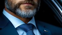Mature businessman with gray beard in luxury car wearing navy suit and tie. Professional executive portrait for corporate business concepts.