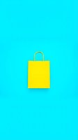 Bright yellow shopping bag with gold handles isolated on vibrant cyan background, ready for retail, e-commerce, and promotional design projects.