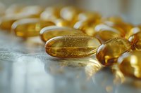 Golden omega-3 fish oil capsules scattered on white surface with soft lighting for health and wellness supplement nutrition concept.