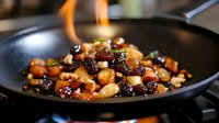 Caramelized nuts and dried fruits sautéed in pan with honey glaze creating sweet and savory mixture with golden flames for gourmet cooking and dessert preparation.