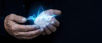 Elderly hands cupping glowing blue energy light with magical particles and luminous effects on dark background for spiritual healing concepts.