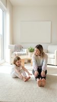 Adult woman and young girl sitting on carpet in bright living room with blank canvas on wall, sofa, and natural light from window. Family bonding moment.