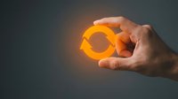 Hand holding glowing orange female gender symbol against dark background, representing feminism, women empowerment, gender equality and women rights concepts.