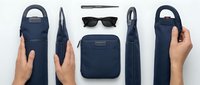 Navy blue leather accessories collection with hands displaying wallet, sunglasses, and bags on white background for modern lifestyle branding.