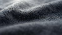 Close-up of soft, textured fabric surface with gentle waves and folds, showcasing material quality for fashion, textile, and design projects.