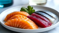 Fresh salmon and tuna sashimi slices arranged on white ceramic plate with parsley garnish, showcasing vibrant orange and deep red colors of premium raw fish.