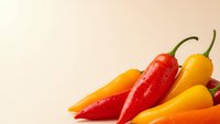 Fresh colorful hot chili peppers in red, yellow and orange arranged on light background for cooking, spice and culinary ingredient concepts.