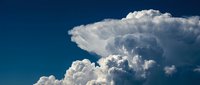 Dramatic white cumulus clouds against deep blue sky creating powerful weather formation with billowing texture and natural light for meteorology concepts.