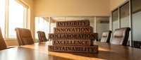 Modern office conference room with wooden blocks displaying corporate values integrity innovation collaboration excellence sustainability on table.
