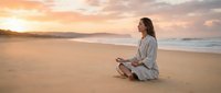 Young woman practicing meditation on sandy beach during golden sunset with peaceful ocean waves and colorful sky for wellness and mindfulness concepts.