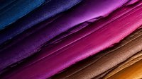 Diagonal rows of colorful leather or textile material samples arranged in gradient from blue through purple, pink, brown to yellow, showing texture and surface detail.