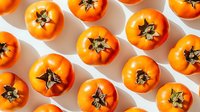 Fresh ripe orange tomatoes arranged in rows on white background, top view pattern composition for food photography and healthy eating concept.