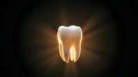 Glowing white tooth with golden light rays on dark background for dental care and oral health concepts.