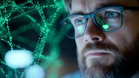 Bearded male scientist with glasses analyzing digital DNA structure visualization in green neon light. Modern biotechnology and genetic research concept.