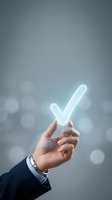 Businessman hand holding glowing white checkmark symbol against blurred bokeh background representing success, approval, and achievement in corporate environment.