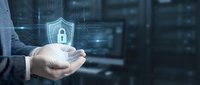 Businessman holding glowing cybersecurity shield with padlock icon over palm in modern digital technology environment for data protection concepts.