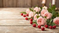 Pink garden roses and fresh raspberries arranged on rustic wooden surface with blurred background, suitable for floral design, greeting cards, and seasonal marketing materials.