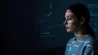 Young woman with digital data projections on face analyzing futuristic holographic interface in dark tech environment for business presentations.