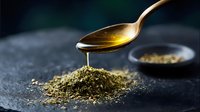 Golden honey dripping from spoon onto aromatic dried herbs and spices mix on dark stone background, macro food photography for culinary design.