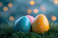 Colorful Easter eggs decorated with stars and dots nestled in green grass with soft bokeh lights creating magical holiday atmosphere. Perfect for seasonal designs.