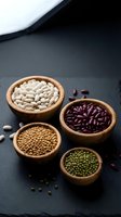 Assorted legumes in wooden bowls on dark slate surface featuring white beans, kidney beans, lentils and mung beans for healthy cooking and nutrition.
