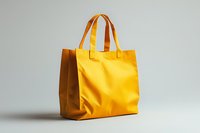 Yellow canvas tote bag with leather handles isolated on light gray background, minimalist design for shopping and everyday use, eco-friendly accessory.