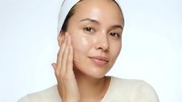 Young Asian woman applying facial cream skincare routine beauty treatment moisturizer anti-aging cosmetics wellness self-care healthy skin glowing complexion.