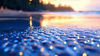 Tranquil ocean waves at sunset create mesmerizing bokeh effect on water surface, with golden light reflections and ripples forming magical pattern on blue sea.