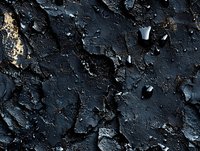 Dark peeling paint texture with cracked and chipped surface showing weathered layers and rough deterioration, creating dramatic shadows and depth on black wall.