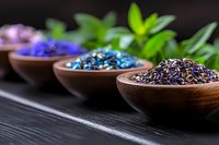 Aromatic dried flower petals and herbs in wooden bowls on dark background, selective focus on colorful natural ingredients for tea, spa treatments and aromatherapy.