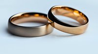 Two elegant wedding bands in silver and rose gold tones lying together on white surface, symbolizing marriage, commitment and eternal love.