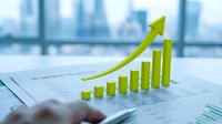 Green growth chart with upward arrow on financial documents in modern office setting showing business success and profit increase trends.