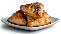 Golden baked pastries with herbs and seeds stacked on white plate, isolated on white background for culinary designs and food marketing materials.
