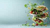 Flying ingredients and fresh vegetables around Mexican street tacos with beef, tomatoes, onions and cilantro on turquoise background with copy space.