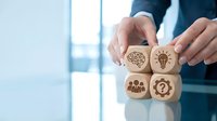 Business professional protecting wooden blocks with innovation icons including brain, lightbulb, team and gear symbols for strategic planning concepts.