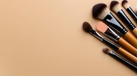 Professional makeup brushes set with soft bristles arranged on beige background, minimal cosmetic flatlay composition for beauty and fashion content.