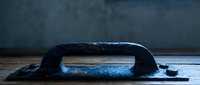 Vintage black metal hand plane woodworking tool on wooden surface against dark blue wall background for carpentry and craftsmanship projects.