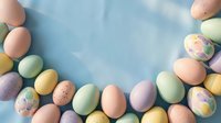 Pastel Easter eggs arranged in a semicircle frame on a soft blue background, leaving copy space in the center for text or design.