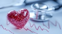 Red glittery heart shape on medical cardiogram paper with stethoscope in background, representing cardiovascular health and heart disease prevention concept.