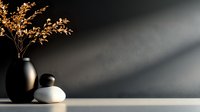 Minimalist zen composition with black and white ceramic vases and dried golden branches against dark wall, diagonal sunbeam creates dramatic atmosphere.