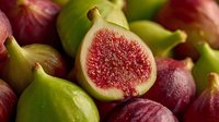 Fresh ripe figs cut in half showing red flesh and seeds surrounded by whole purple and green figs with leaves for healthy eating and cooking.
