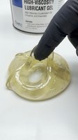 High-viscosity lubricant gel being applied with a gloved hand, showing thick, translucent yellow substance for industrial and mechanical applications.