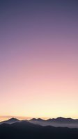 Stunning mountain silhouettes against vibrant purple pink sunset sky with atmospheric haze creating dreamy landscape for nature backgrounds.