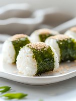 Fresh sushi rolls with seaweed, white rice and sesame seeds served on white plate. Close up view of Japanese cuisine with selective focus.
