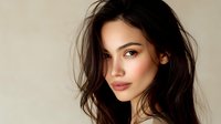 Young woman with long dark hair and natural makeup against neutral beige background, showcasing soft lighting and flawless complexion for beauty and fashion advertising.